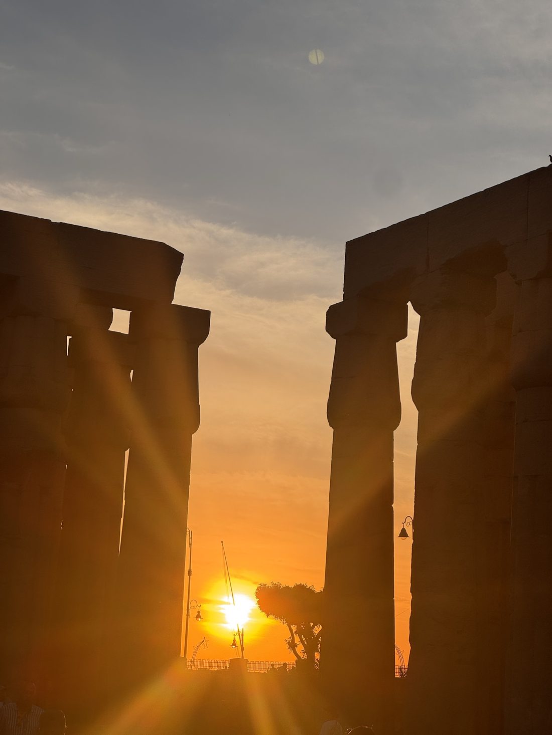 The sun setting directly between two column silhouettes at Luxor Temple